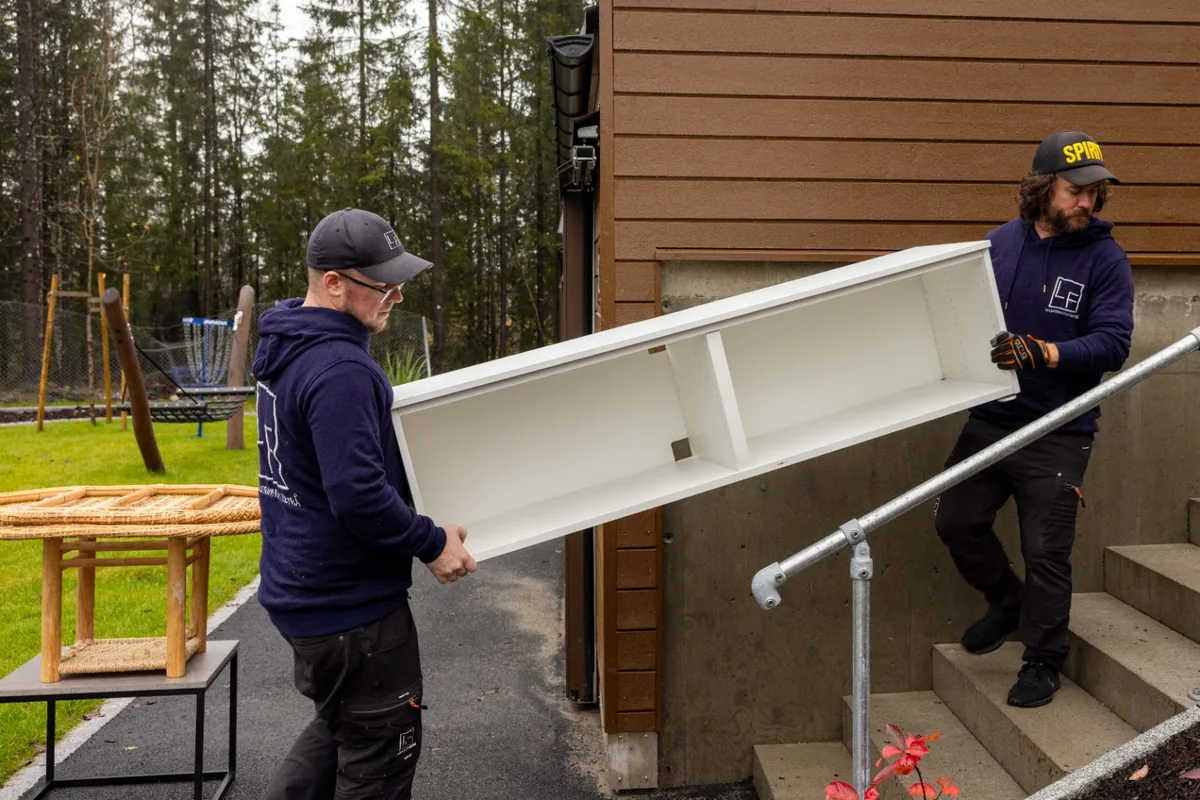 To flyttemedarbeidere bærer et møbel ved en bolig